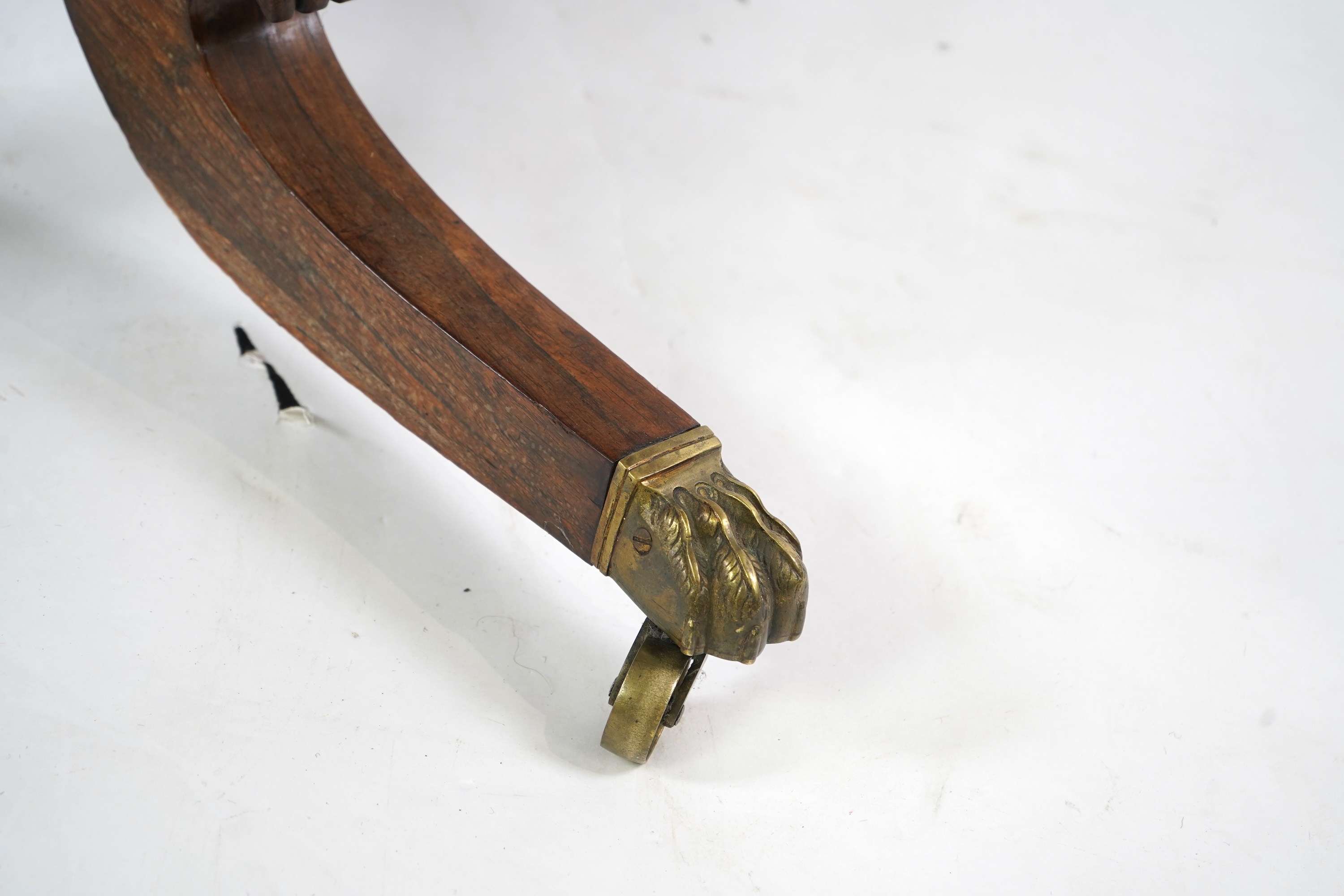 A Regency cut brass inlaid and gilt metal mounted circular rosewood breakfast table, the bird's-eye maple banded tilt top on baluster column, concave platform and quadruple downswept base with cast claw caps and castors,